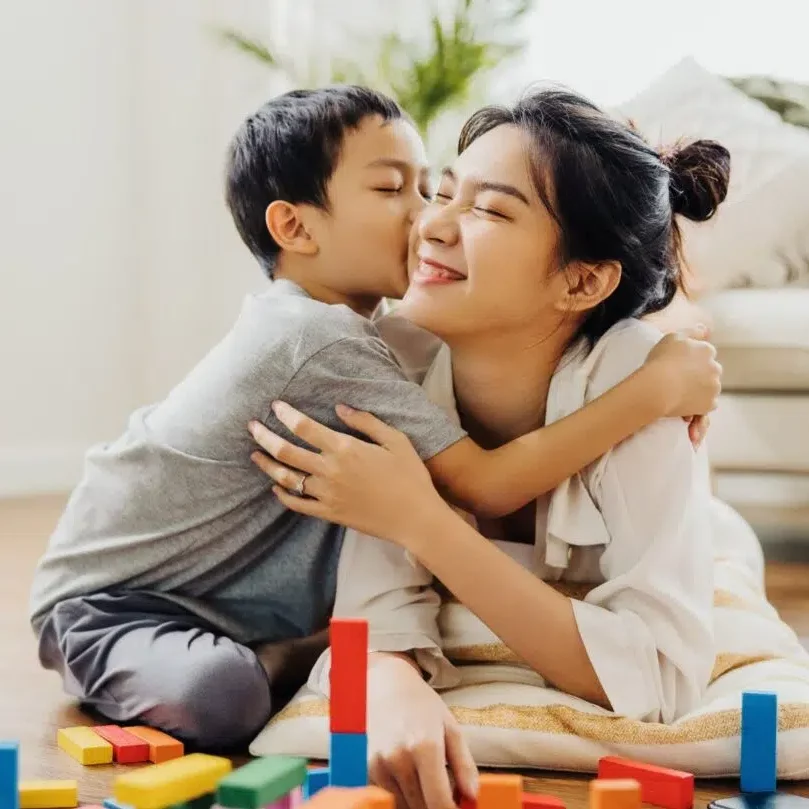 Kid hugging his mom while playing blocks